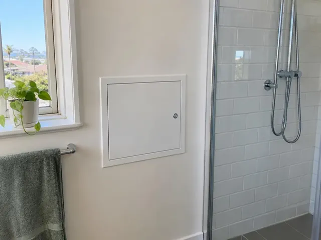 Neat access panel on a painted bathroom wall beside a tiled shower in Coogee